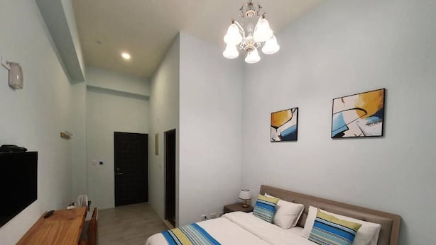 A bedroom with a bed, bedside table, lamp, and artwork on the wall.