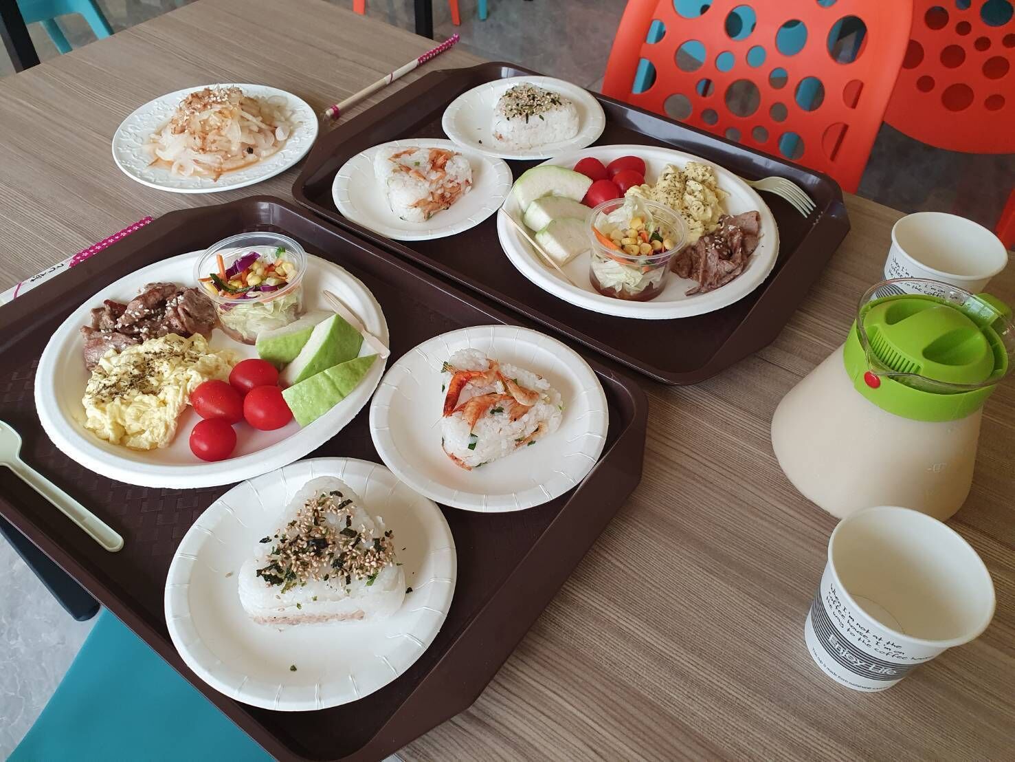 Una bandeja con diferentes platos, incluyendo sushi, ensalada y carne, además de una botella de agua sobre una mesa.