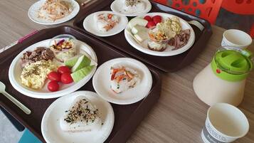 Una bandeja con diferentes platos, incluyendo sushi, ensalada y carne, además de una botella de agua sobre una mesa.