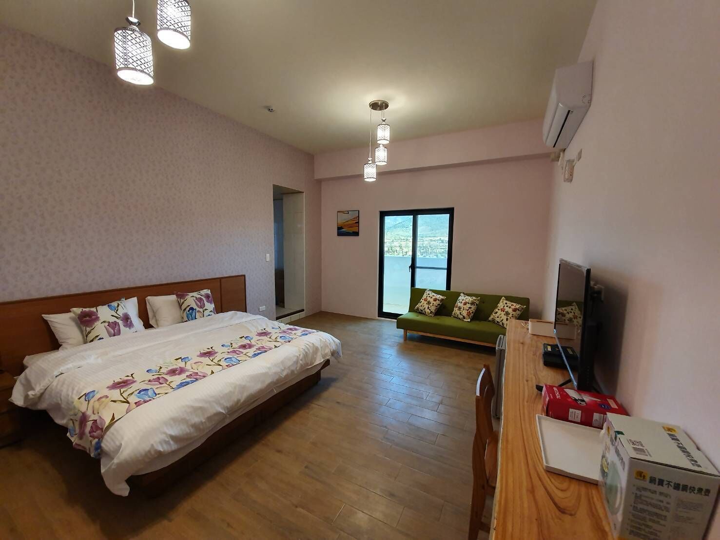 A hotel room with a bed, a sofa, a TV, and a wooden desk.