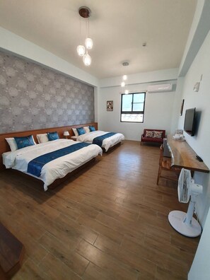 Ein Schlafzimmer mit zwei Betten, einem Schreibtisch, einem Stuhl, einem Fernseher und einem Fenster.
