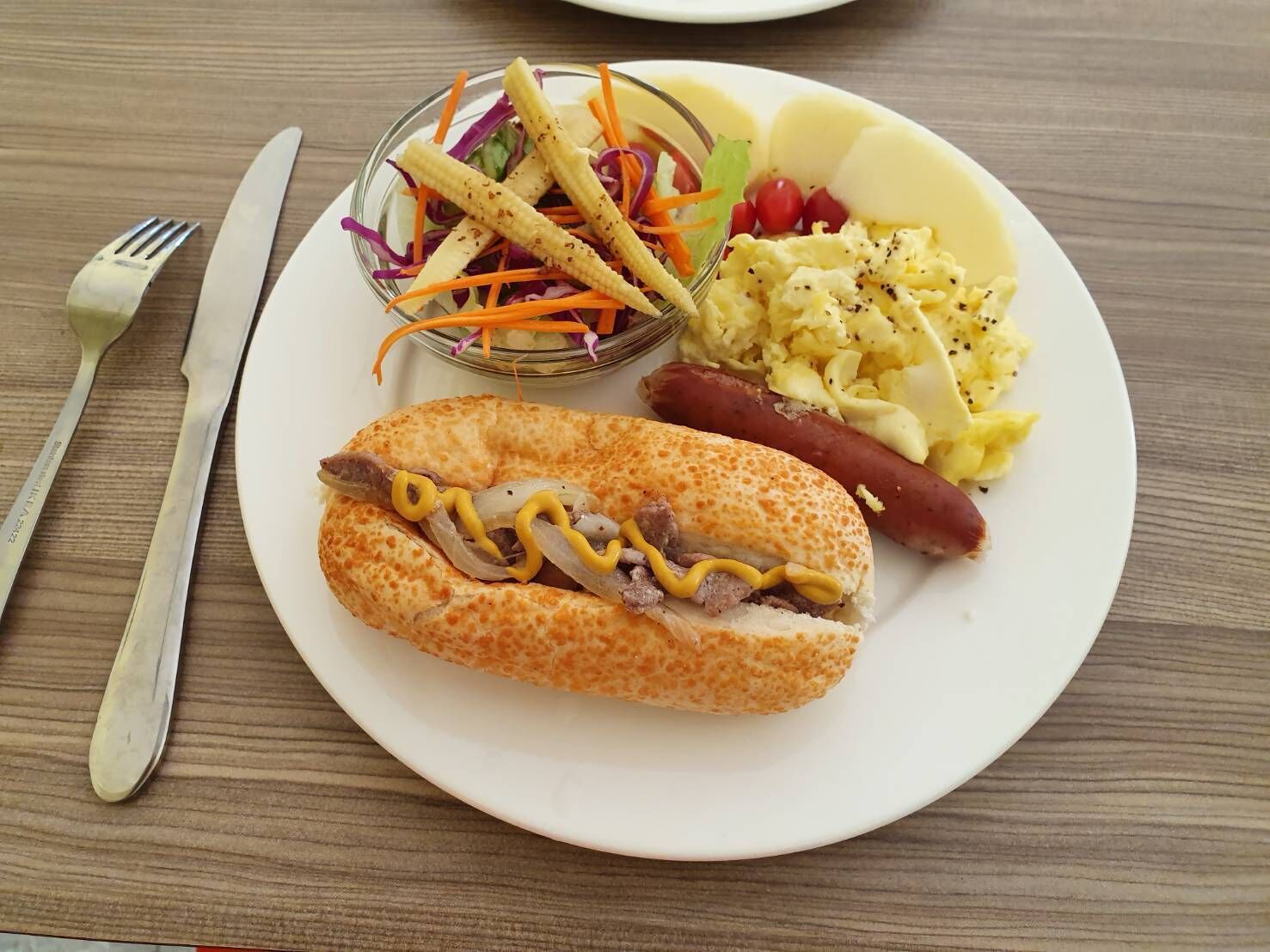 A plate with a hot dog, a sandwich, coleslaw, and scrambled eggs.