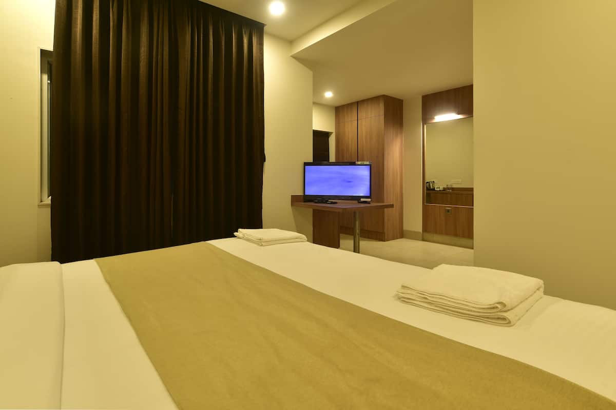 Habitación de hotel con cama, televisor, mueble de madera y espejo.