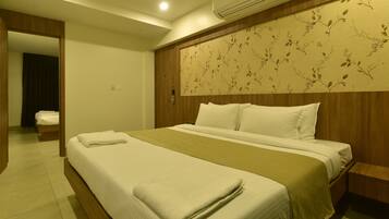 A hotel room with a large bed, a wooden headboard, and a visible air conditioning unit.
