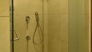 A glass-enclosed shower with a handheld showerhead and a wall-mounted faucet. - Panchavati Express (Nashik)
