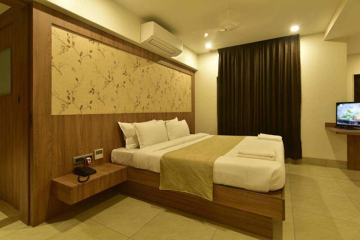 Una habitación de hotel moderna con un marco de cama de madera, un televisor de pantalla plana y un teléfono junto a la cama.