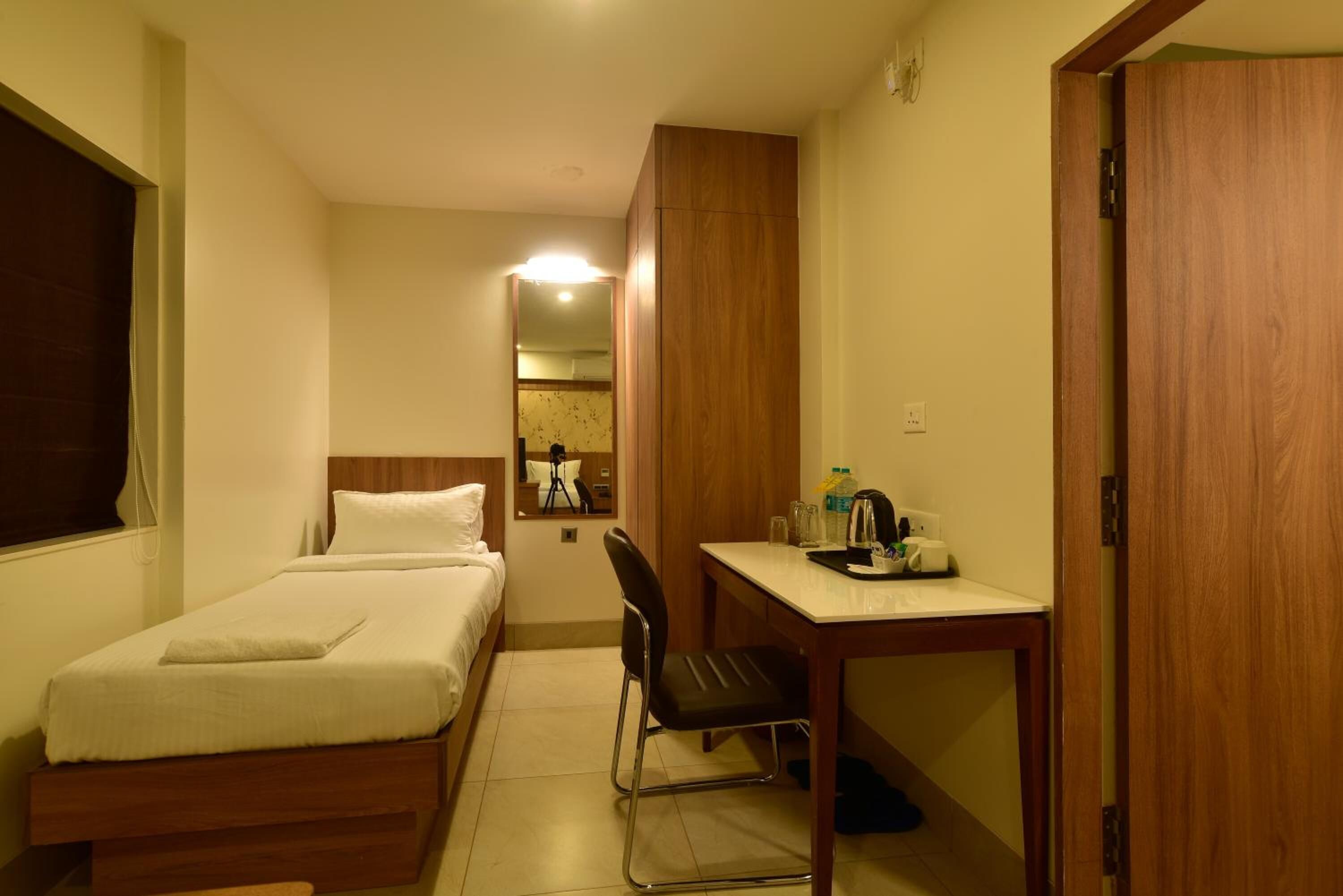 Una habitación de hotel con cama, escritorio, silla y armario.