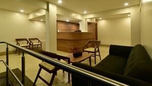A modern hotel lobby with a reception desk, seating area, and a staircase. - Panchavati Express (Nashik)