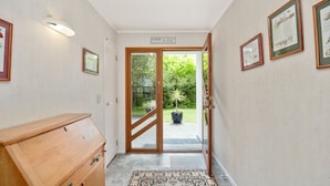 Un couloir avec une armoire en bois, un tapis et une porte donnant sur un jardin.