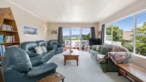 Un salon spacieux avec des canapés en cuir, une table basse en bois et une bibliothèque. De grandes fenêtres offrent une vue sur l’extérieur.