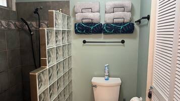 A bathroom with a shower, toilet, and towel rack.