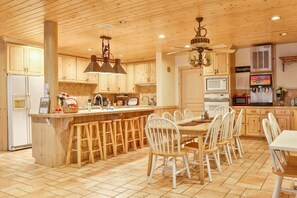 Una cocina amplia con armarios de madera, una isla central con taburetes, un ventilador de techo y un microondas.