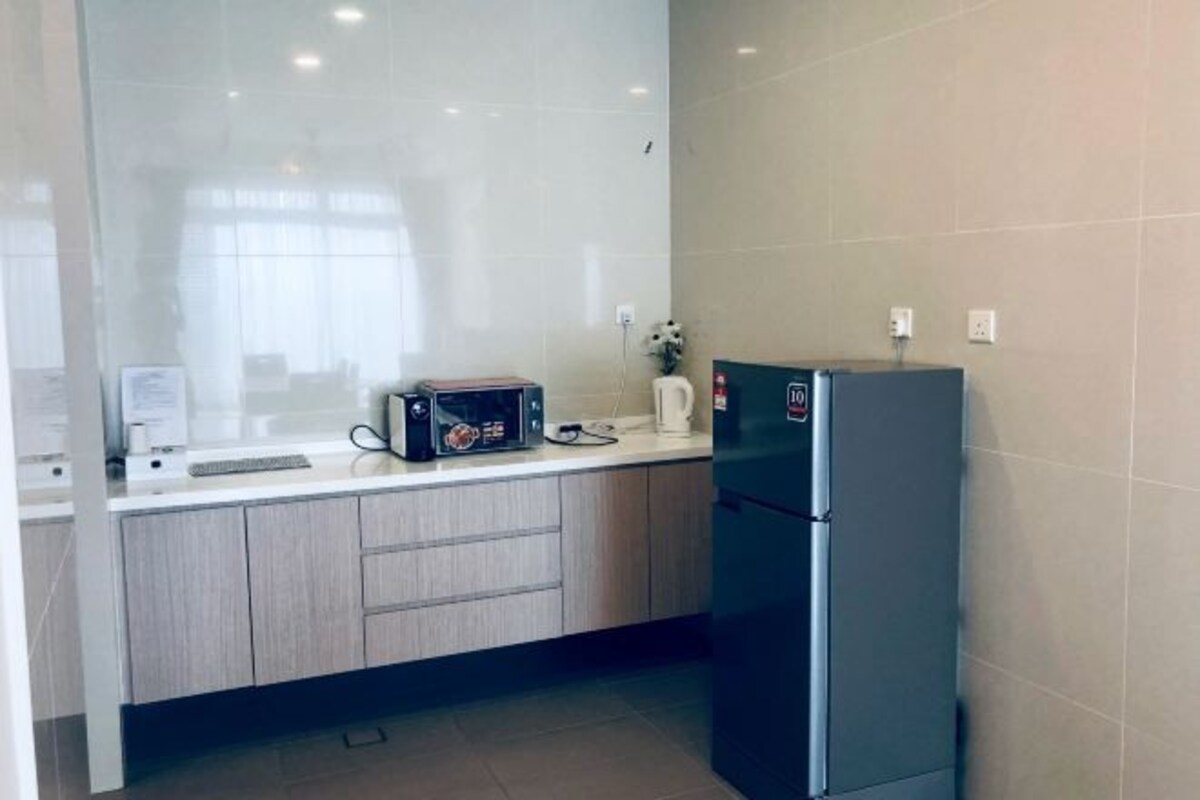 A modern kitchen with a refrigerator, microwave, and a coffee maker on the counter.