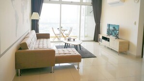 A modern living room with a sofa, a coffee table, a TV, and a balcony with a view. - KSL D’Esplanade by Antlerzone (Johor Bahru)