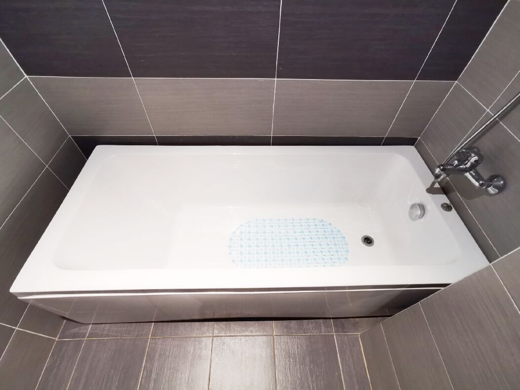Une baignoire rectangulaire dotée d’un siège intégré, d’un robinet et d’un drain.