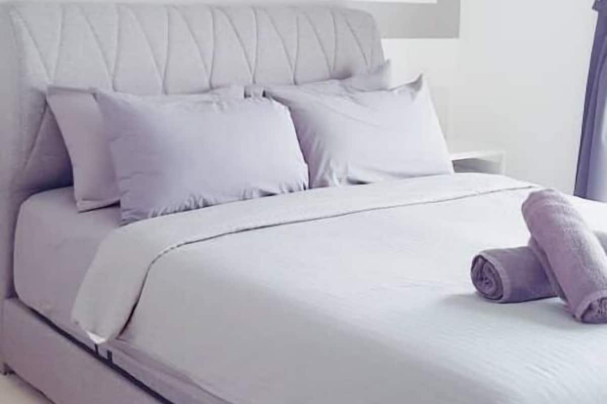 A modern bedroom with a bed, pillows, and a wall art piece.