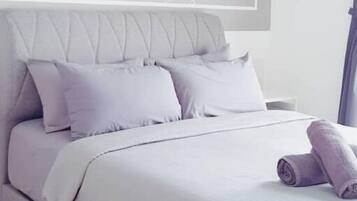 A modern bedroom with a bed, pillows, and a wall art piece.