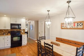 A kitchen with white cabinets, a black stove, and a dining area with a wooden table and chairs.