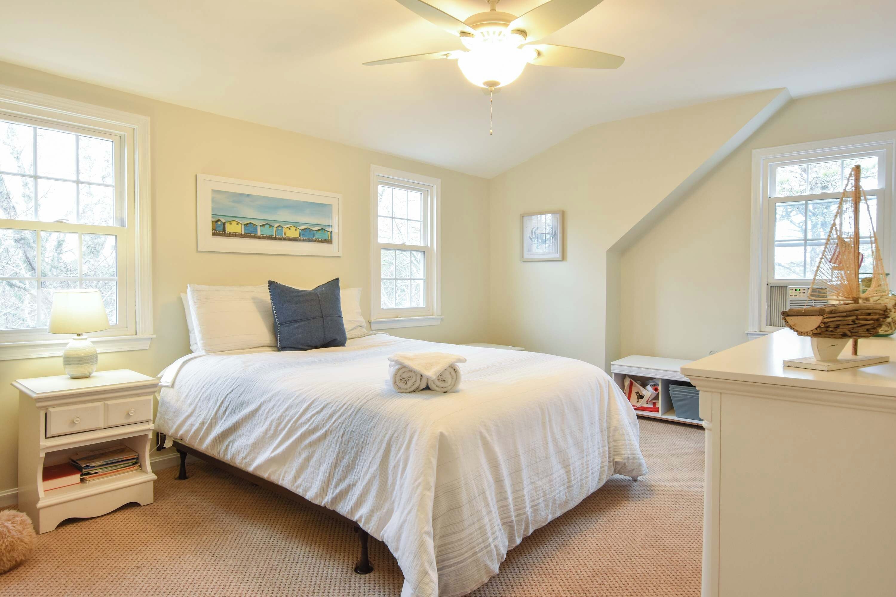 A bedroom with a bed, nightstands, a lamp, and a ceiling fan.