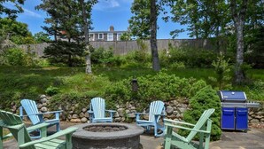 A backyard with Adirondack chairs, a stone fire pit, and a barbecue grill. - Spacious w/ Large Outdoor Area Fire Pit! (Chatham)