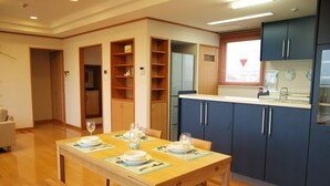 Un coin repas avec une table en bois dressée pour quatre personnes, bordé de meubles bleus et donnant sur une fenêtre avec vue.