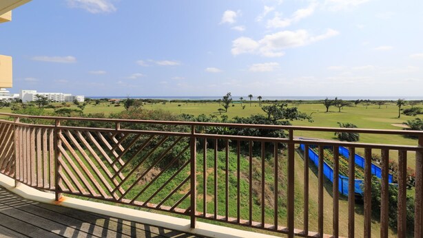 Un balcon avec vue sur un terrain de golf et un bâtiment situé au loin.