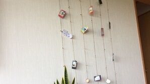 Une pièce dont un mur est décoré d’objets suspendus de différentes sortes, ainsi que d’une plante en pot et d’un sac à motifs.