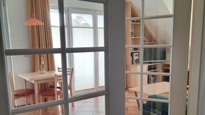 Una habitación con comedor, un sofá y una escalera que conduce a un nivel superior.
