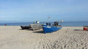 Dos barcos en una playa arenosa con el océano al fondo.
