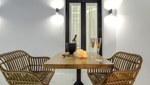 A dining table with two wicker chairs, candles, and champagne glasses. - Two Bedroom Apartment, Diadema Apartments Naxos (Naxos)