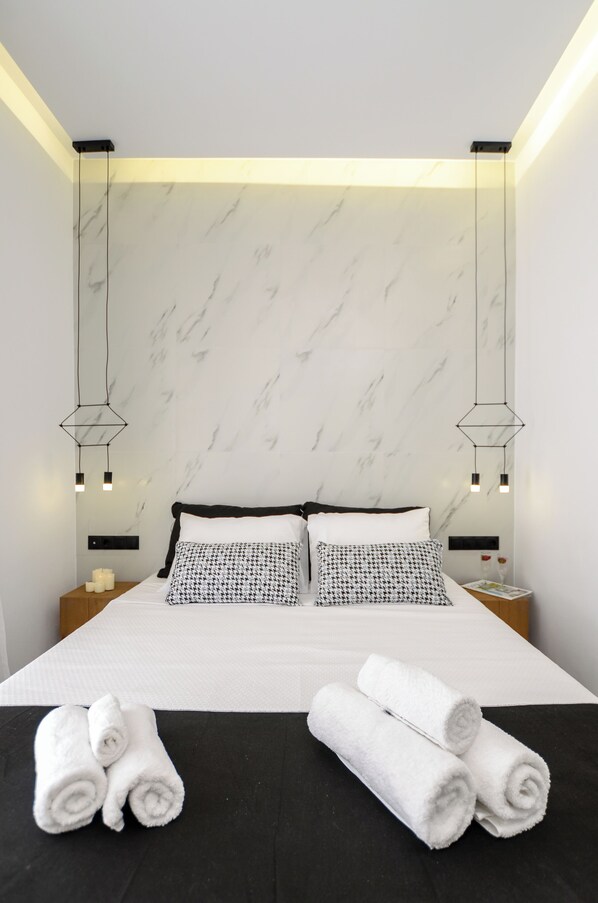 Une chambre d’hôtel moderne avec un grand lit, deux tables de chevet et un mur décoré d’un motif imitant le marbre.