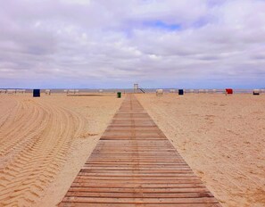 A wooden boardwalk leading to beach chairs and a lifeguard stand.