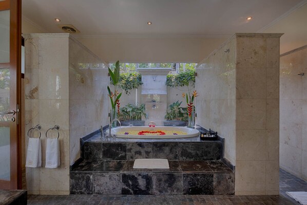 Un espace spa doté d’une grande baignoire, de marches en marbre et de plantes en pot.