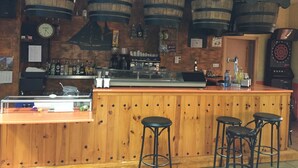 A bar area with wooden barrels, a clock, and stools. - Camping Los Molinos (Palacios de Sanabria)