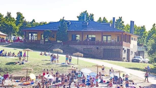 A beachside resort with a large building, a grassy area, and a sandy beach. - Camping Los Molinos (Palacios de Sanabria)