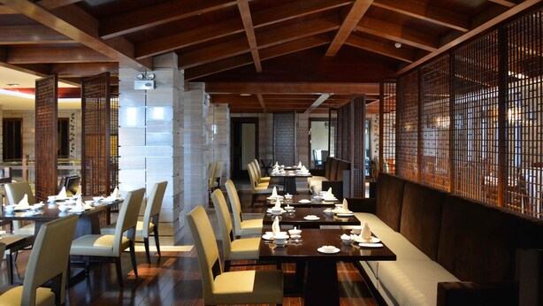 A restaurant with wooden beams, a long dining table, and traditional Asian-style partitions. - Su Tang Hotel (Changsha)