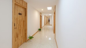 A long, narrow hallway with wooden doors on one side and a tiled floor. - Su Tang Hotel (Changsha)