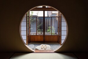 A traditional Japanese room with tatami flooring, a shoji screen door, and a view of a garden through the screen. - Kurohoro (Kanazawa)