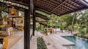 A spacious outdoor area with a pool, wooden deck, and seating arrangements.