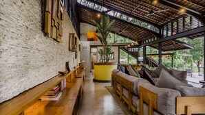 A spacious lobby with a high ceiling, a wooden bench, a sofa, and a staircase leading to an upper level.
