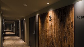 Un couloir d’hôtel avec des lambris en bois, des portes numérotées et un sol recouvert de moquette.