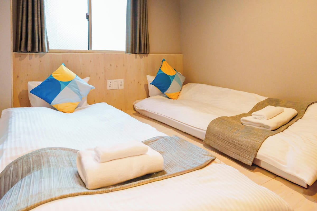 A hotel room with two single beds, each with a pillow and a blanket.