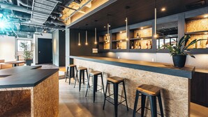 Un espace bar avec des tabourets, un comptoir et des étagères remplies de bouteilles.