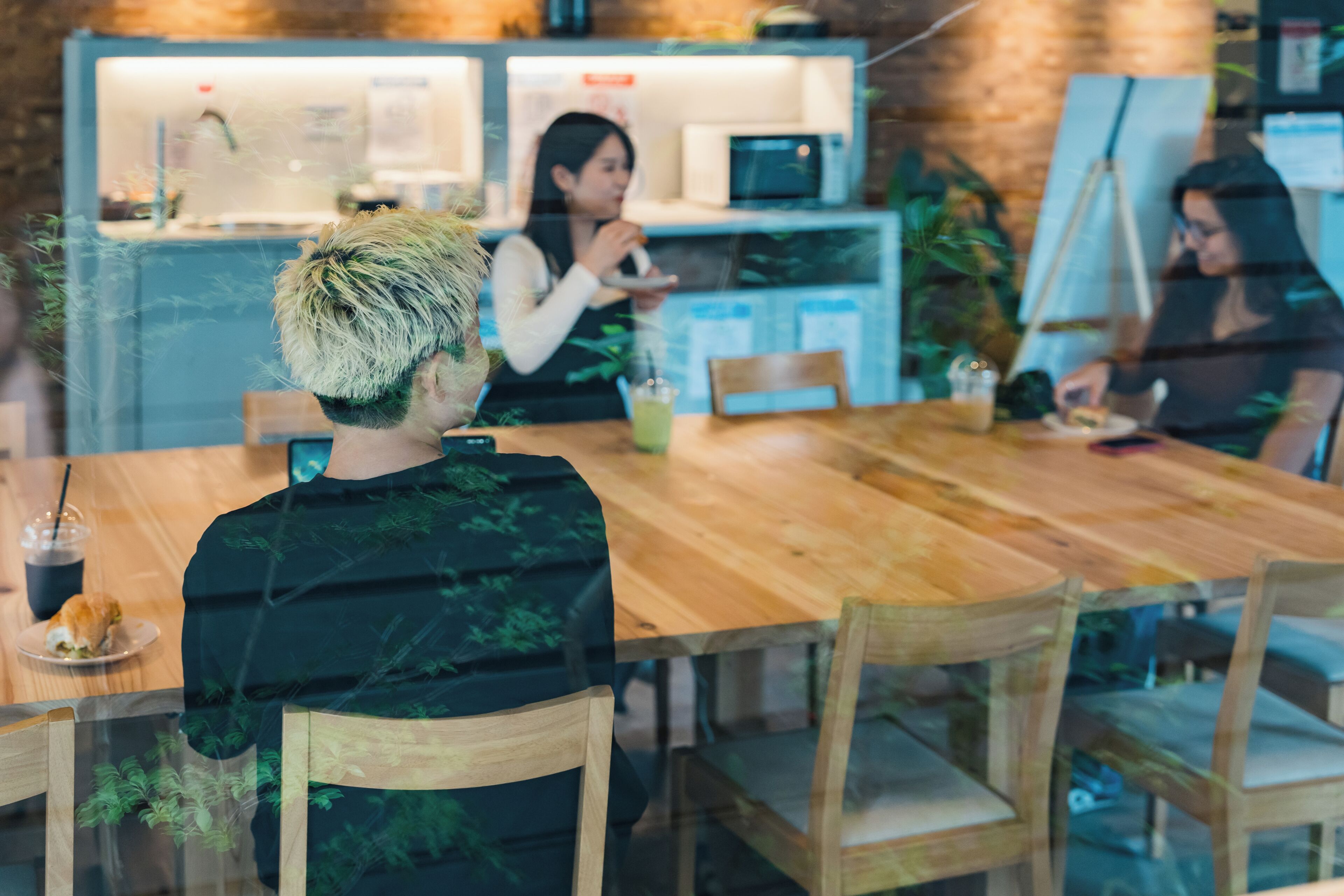 A restaurant with wooden tables and chairs, a counter with a menu, and a painting on the wall.