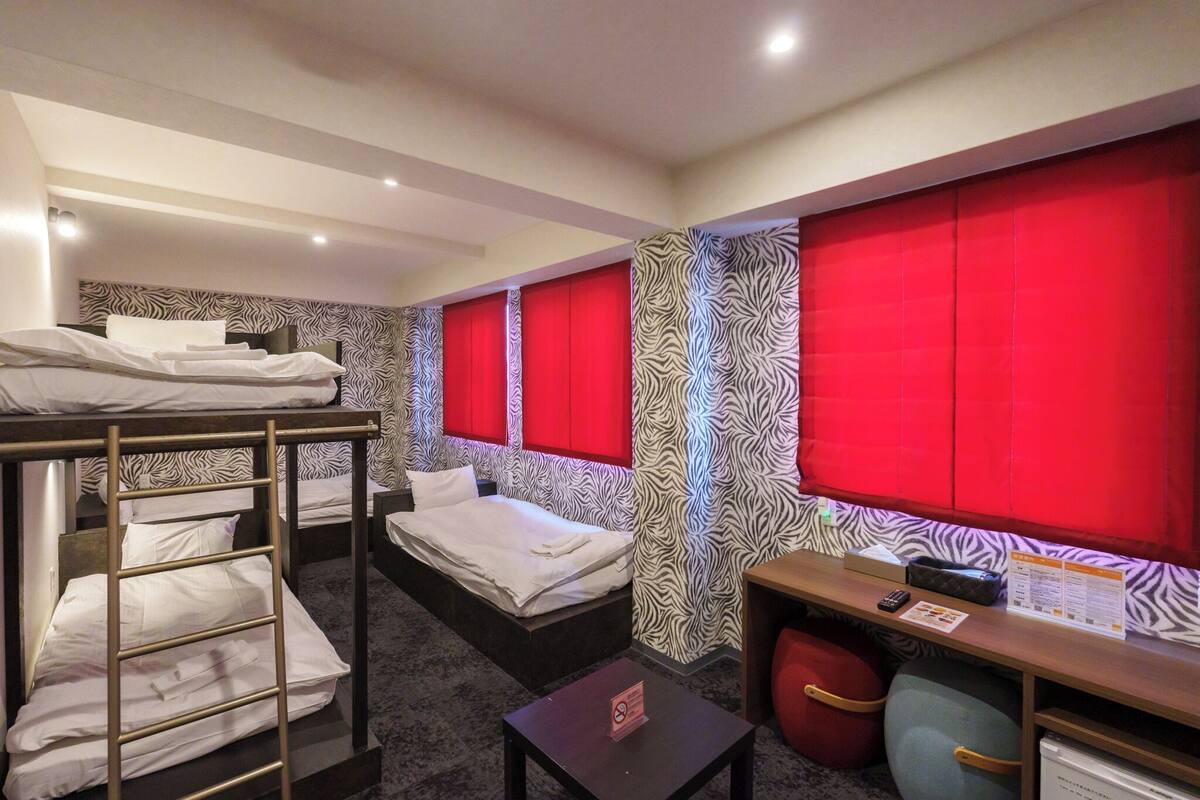A hotel room with bunk beds, a desk, and a red accent wall.