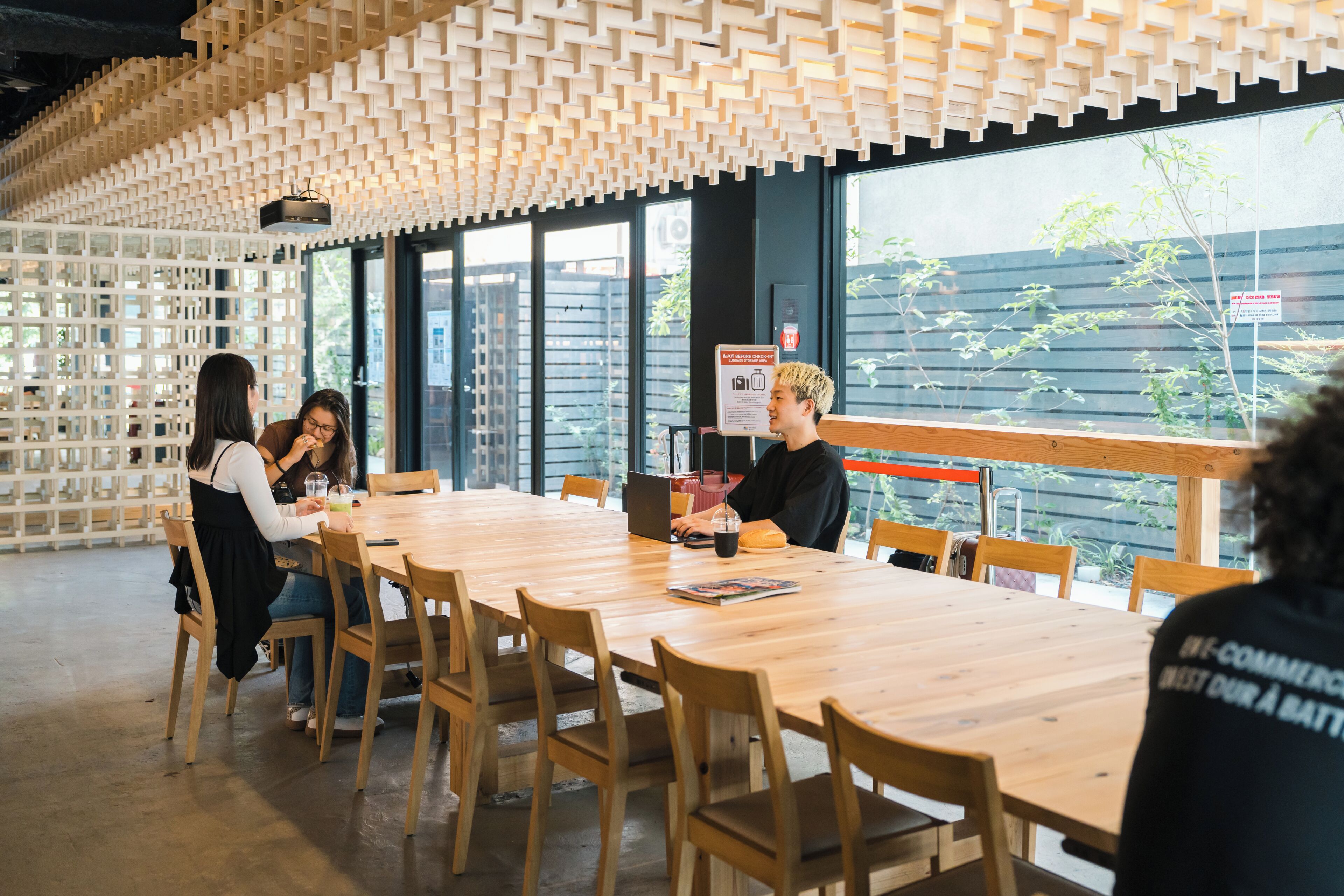 A conference room with a wooden table and chairs, large windows, and a unique ceiling design.