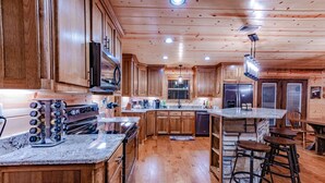 A spacious kitchen with wooden cabinets, granite countertops, and a central island with bar stools.