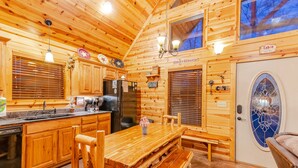 L’intérieur d’un chalet en bois comprend une cuisine, un coin repas et une porte ornée d’un vitrail décoratif.