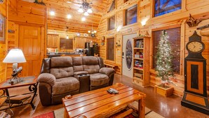 L’intérieur chaleureux d’un chalet en bois, avec une cheminée, un canapé en cuir, une table à manger et un sapin de Noël.