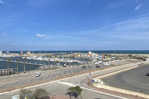 A marina with boats docked, a parking area, and a road leading to the beach. - Apartment in Le Lotus Blanc with Sea View (Le Barcares)